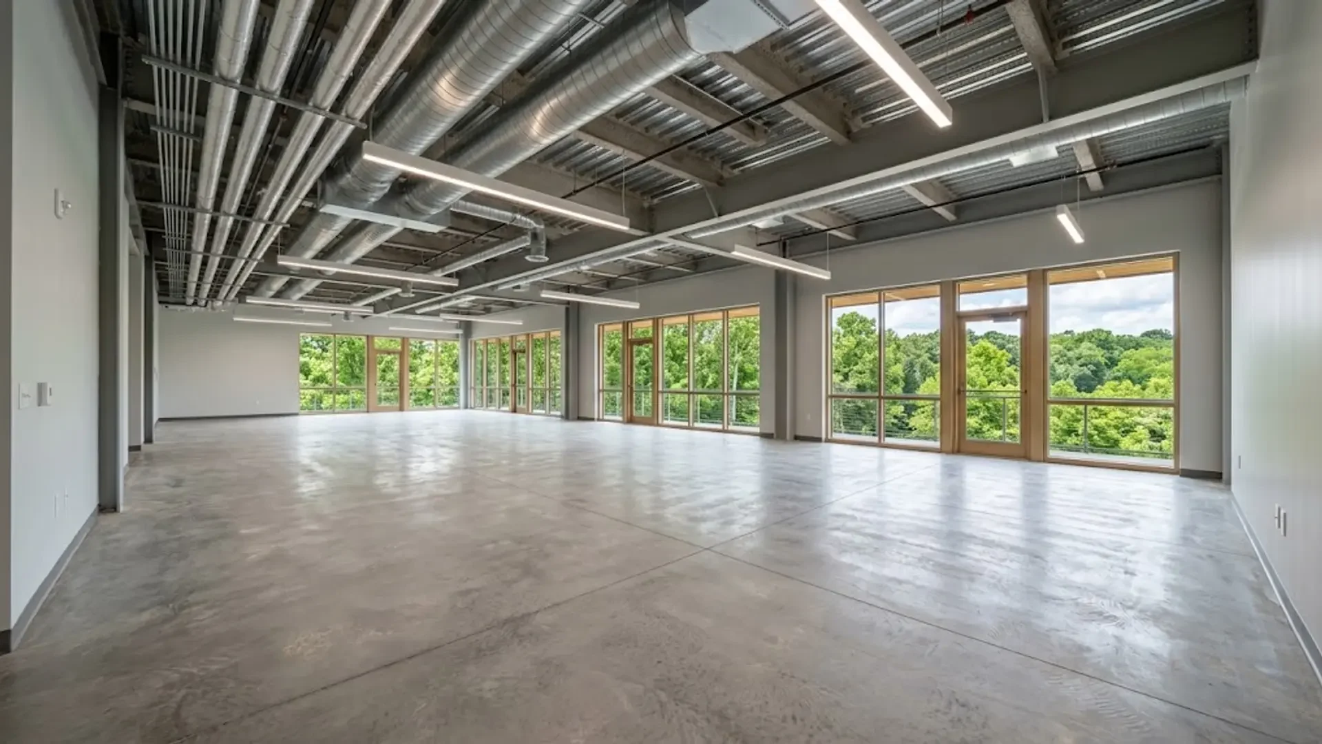 Concrete floor in an empty commercial interior with exposed HVAC ductwork